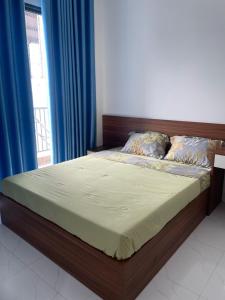 a bedroom with a bed with blue curtains and a window at CH Home in Danang