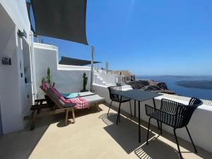 a balcony with a table and chairs and a view at Imera Vista Suites in Imerovigli