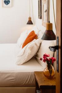 a bed with pillows and a vase with flowers on a table at Can Vistabella Boutique Resort in San Antonio +59 photos