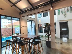 a dining room with a wooden table and stools at D'Pasir Lodge in Malacca