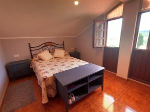 a bedroom with a bed with a table and two windows at El Blao, preciosa casa para 6-7 personas a 1km de Arriondas in Arriondas
