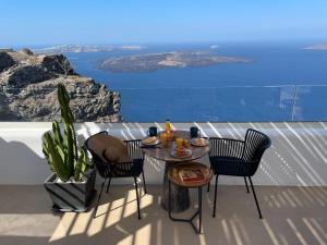 Imera Vista Suites في إيميروفيغلي: طاولة وكراسي على شرفة مطلة على المحيط