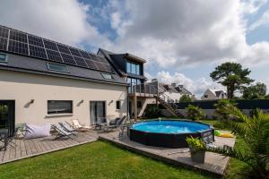 a house with a swimming pool with solar panels on the roof at Villa Clémarine in Saint-Philibert