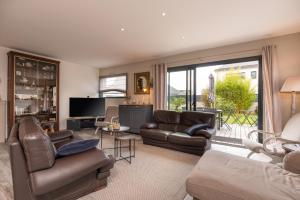 a living room with leather furniture and a large window at Villa Clémarine in Saint-Philibert