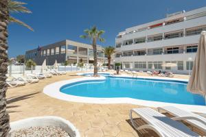 a swimming pool with lounge chairs and a building at Azahara Beach in Arona