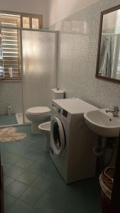 a bathroom with a washer and a toilet and a sink at La casa di Sonia in Fanusa +2 photos