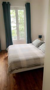 ein Bett in einem Schlafzimmer mit einem großen Fenster in der Unterkunft Appartement saint ouen 45M2 in Saint-Ouen