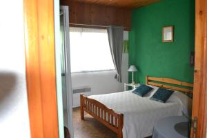 a bedroom with a bed with green walls and a window at Les Fromentines in Saint-Pol-de-Léon