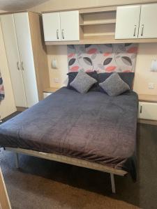 a large bed in a room with white cabinets at Whitehouse Leisure Park N&V Caravan Hire in Kinmel Bay