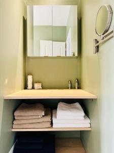 a bathroom with a shelf with towels and a mirror at Le Bon Compromis in Poitiers