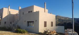 a white house with a hill in the background at Pera Horio House in Apeiranthos