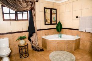 a bathroom with a tub and a toilet at Aloe room in Rustenburg