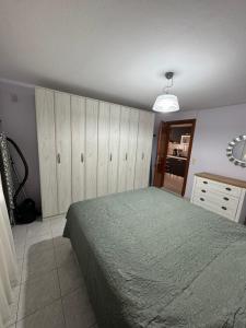 ネア・ペラモスにあるChristinas Deluxe Apartmentのベッドルーム1室(ベッド1台、木製キャビネット、ドレッサー付)