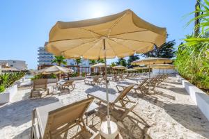 a beach with tables and chairs and an umbrella at Hotel Ankaa - Adults Only in Porto Cristo