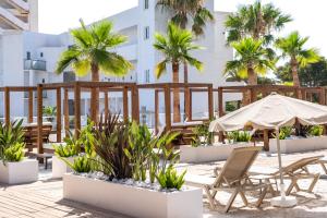 a patio with chairs and umbrellas and palm trees at Hotel Ankaa - Adults Only in Porto Cristo