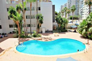 basen z palmami i budynek w obiekcie Xavier - oceanfront apartment with sea views in Calpe w mieście Calpe