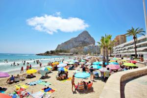 Grupa ludzi na plaży z parasolami w obiekcie Xavier - oceanfront apartment with sea views in Calpe w mieście Calpe