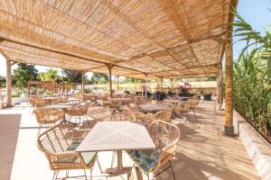 patio ze stołami i krzesłami oraz słomianym parasolem w obiekcie Hotel Ankaa - Adults Only w Porto Cristo