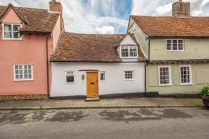 ein weißes Haus mit brauner Tür auf einer Straße in der Unterkunft Brimming with Medieval charm - Weavers Cottage in Lavenham