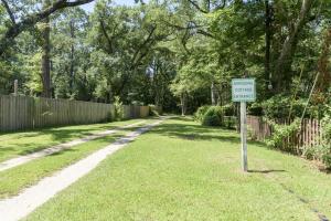 une cour avec un panneau dans l'herbe avec une clôture dans l'établissement Birdsong Cottage, à Freeport