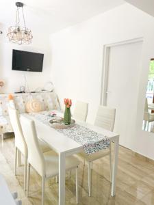 een eetkamer met een witte tafel en stoelen bij Rise of Olympus apartmani in Zadar
