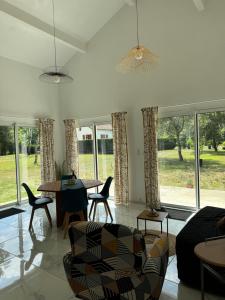 a living room with a table and chairs and windows at Maison 4 personnes avec piscine in Bourriot-Bergonce