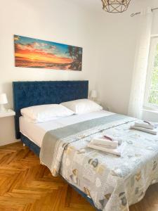 een bed met een blauw hoofdeinde in een slaapkamer bij Rise of Olympus apartmani in Zadar
