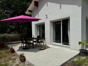 a patio with a table and a purple umbrella at Maison 4 personnes avec piscine in Bourriot-Bergonce +1 photo