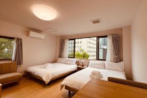 une chambre d'hôtel avec deux lits et une fenêtre dans l'établissement 天王寺令康民泊5ｆ, à Osaka