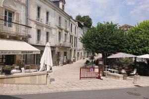 une rue avec un parasol, des tables et des bâtiments dans l'établissement Maison 2 chambres- grand jardin-WIFI - au cœur du village AUBETERRE -visites- conciergerie J&N, à Aubeterre-sur-Dronne
