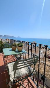 una mesa y una silla en un balcón con vistas al océano en Casa con vistas al mar en el Casco Antiguo de Altea, en Altea