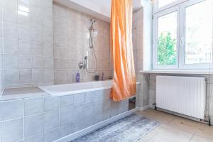 a bathroom with a bath tub and a window at Convenient 3-BR Shared Apt, 15 Min to Landstraße Hub in Vienna +37 photos