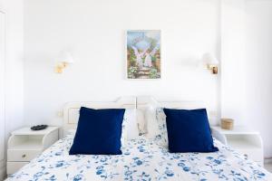 a bed with blue pillows in a white bedroom at EDEN RENTALS Fabulosas Vistas al Mar y Los Acantilados in Acantilado de los Gigantes +70 photos