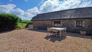 einen Tisch und Stühle vor einem Steingebäude in der Unterkunft Hazel Cottage, Frithelstock in Frithelstock