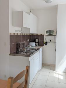 une cuisine avec des armoires blanches et un four à plaques de cuisson dans l'établissement Face à la mer et au sentier de randonnée- Bretagne, à Planguenoual