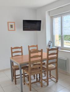une table à manger avec quatre chaises et une télévision dans l'établissement Face à la mer et au sentier de randonnée- Bretagne, à Planguenoual