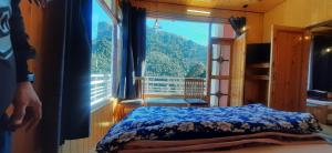 a bedroom with a bed and a large window at THE GROOVE GARDEN DHANOLTi in Dhanaulti