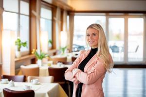 a woman standing in a restaurant with her arms crossed at Hotel Westfalia in Halle an der Saale