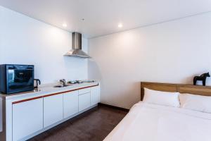 a bedroom with a bed and a sink and a tv at Sea Stay Hotel in Jeju