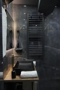 Un baño negro con lavabo y espejo. en Mansarda House, en Tiflis