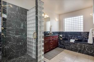 a bathroom with a shower with black marble at Riviera Retreat in Salt Lake with Private Hot Tub and Theater in Millcreek +57 photos