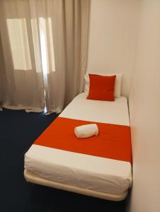 a bed in a room with a red pillow on it at Al-Xelb guesthouse in Silves