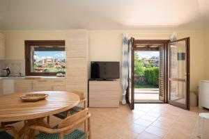 a kitchen and dining room with a table and a television at Villaggio Perlacea - Your House in Sardinia in Golfo Aranci