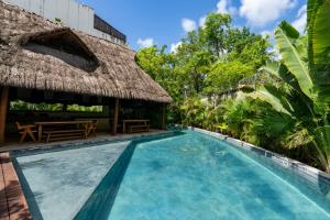 a swimming pool at a resort with a thatch roof at Sapphire - 2 floors condo with private roof and pool & beach club access in Tulum