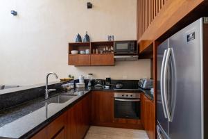 a kitchen with wooden cabinets and a stainless steel refrigerator at Sapphire - 2 floors condo with private roof and pool & beach club access in Tulum