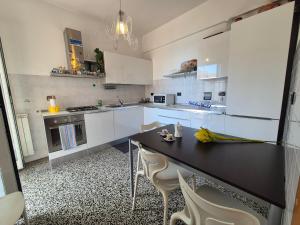 Una cocina con gabinetes blancos y una mesa y sillas. en Casa Gagge by Holiday World, en Génova