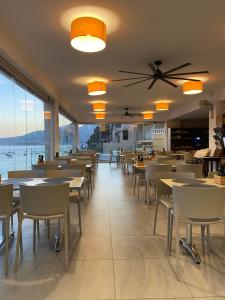 a restaurant with tables and chairs and a view of the ocean at Hostal Dragonera in Sant Elm