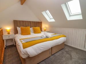 a bedroom with a large bed with yellow pillows and windows at The Bullseye in Stonehouse