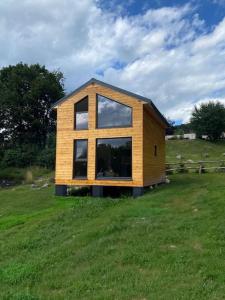a small house sitting on top of a lush green field at Tiny house & AC in Banská Štiavnica