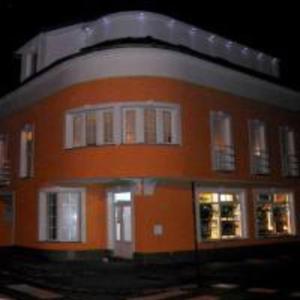 an orange building with white windows and doors at night at Villa Lucia - Apartments&Rooms in Slavonski Brod